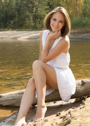 Белая совершеннолетняя подросток демонстрирует свое обнаженное тело на бревне, выброшенном на берег